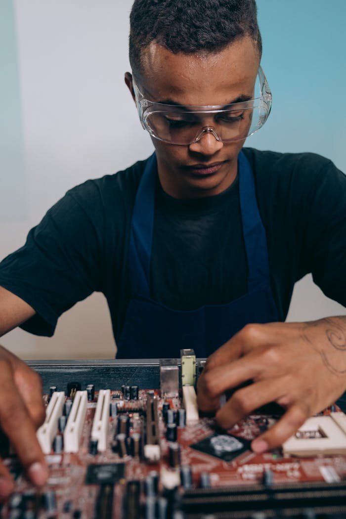 Focused young technician repairing a circuit board with precision indoors.