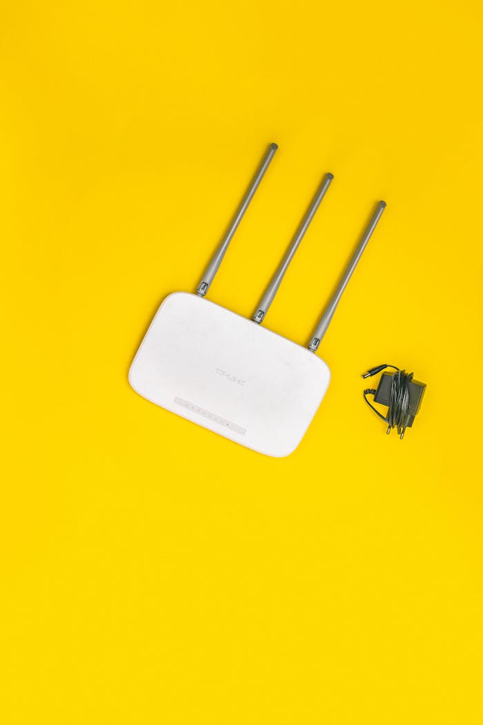 White router with three antennas and cables on bold yellow background, ideal for tech concepts.
